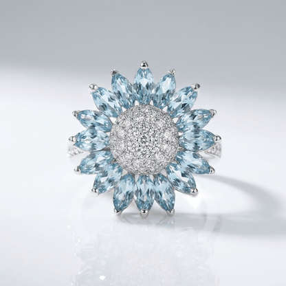 Anillo de plata con topacio azul en forma de flor, de la marca Rose & Oliver, con detalles delicados y piedras brillantes.