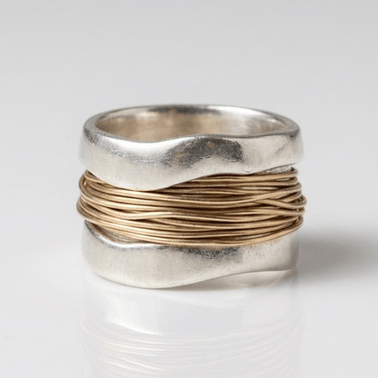 Handgefertigter Ring aus Silber und Gold mit verschlungenen Kabeln, kreiert von der Marke Rose & Oliver, dargestellt auf einem neutralen Hintergrund.