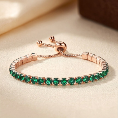 Pulseira ajustável de tênis com ouro e esmeraldas, marca Rose & Oliver, exibindo detalhes elegantes e pedras verdes brilhantes.