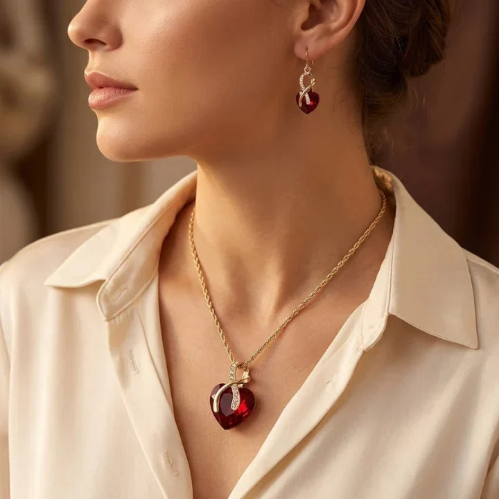 Conjunto de joyas Rose & Oliver con corazón torcido en oro y rubíes, que incluye aretes y collar delicado con piedras rojas.